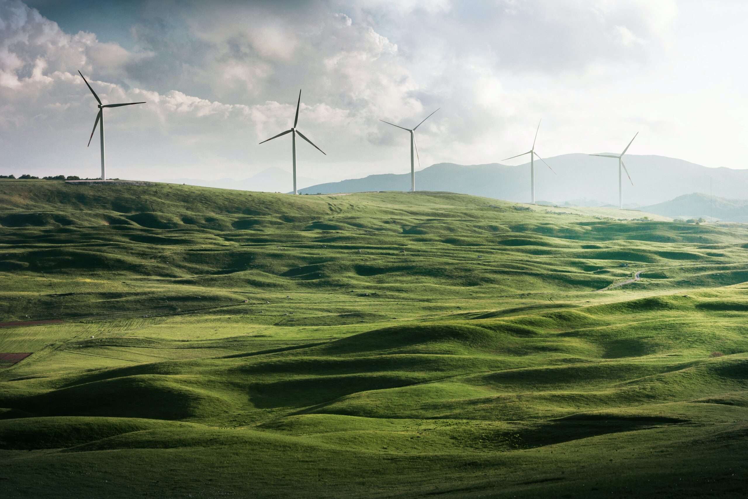 Windmills spinning over rolling green hills