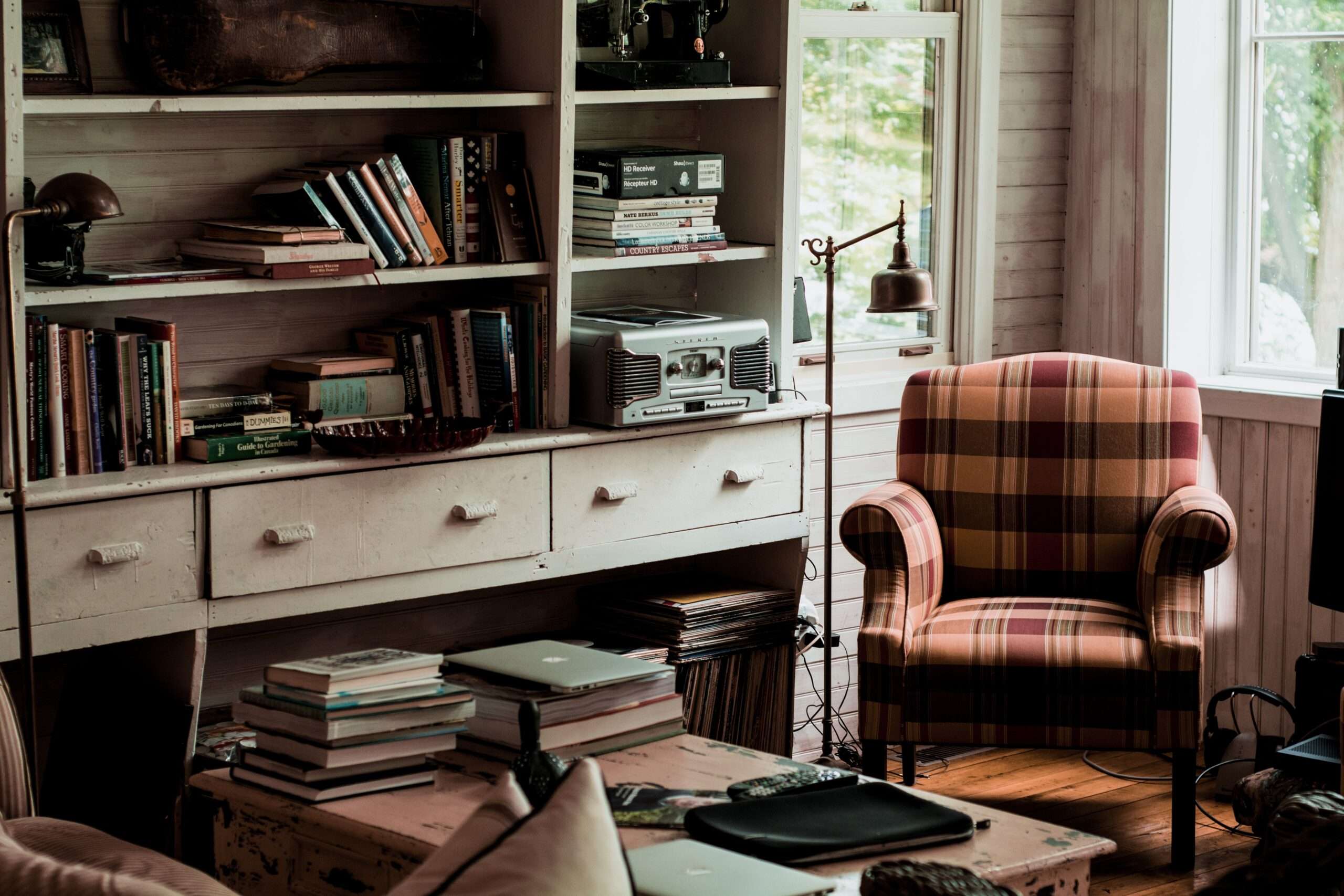 An image of a home office study filled with books, a computer, lamp and overstuffed chair.